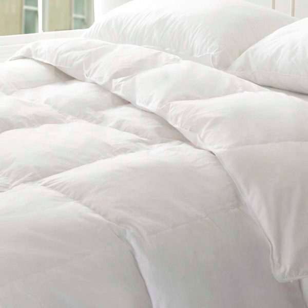 Edredones para cama nórdicos Edredón de cama blanco sobre una cama con almohadas y una mesita de noche.