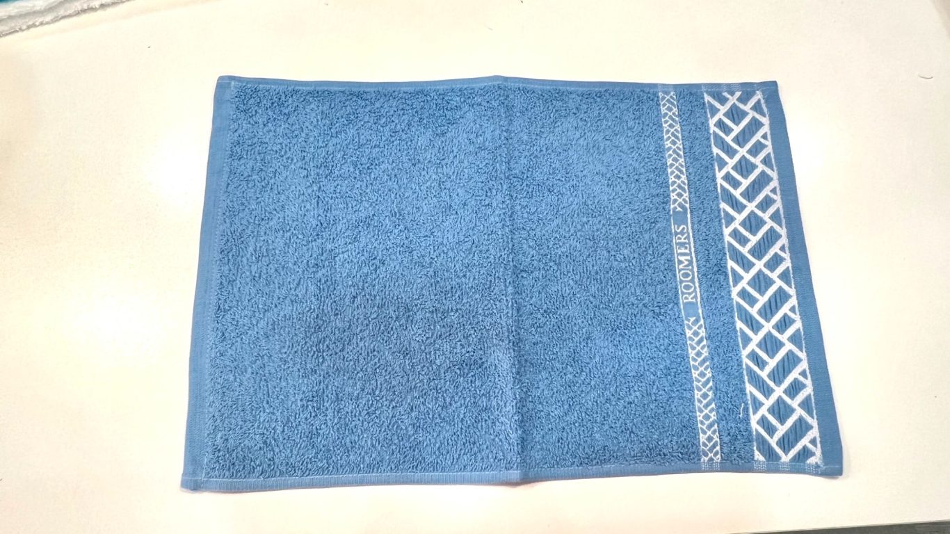 Toalla azul con un diseño bordado en un lado.