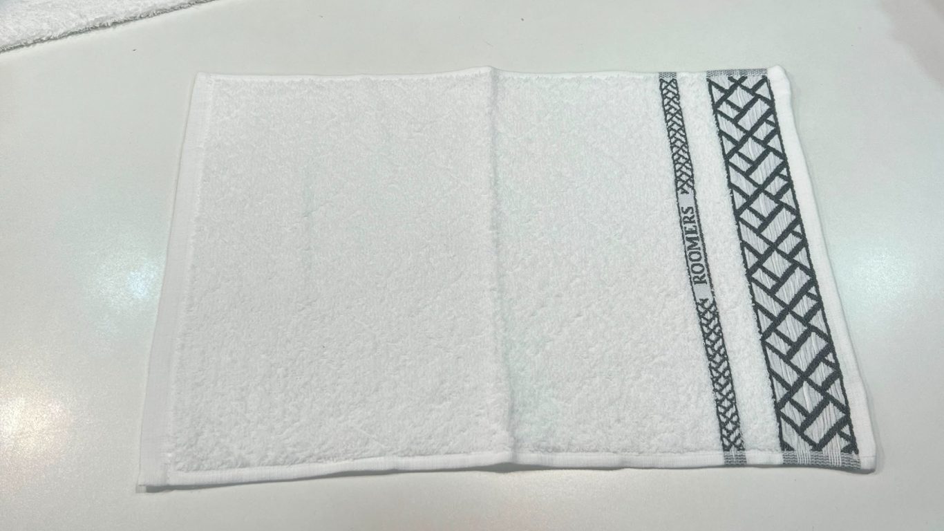 Toalla blanca con borde negro decorativo en un lado.
