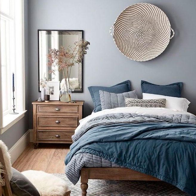 Habitación con cama grande, paredes azules, mesita de noche y decoración elegante.