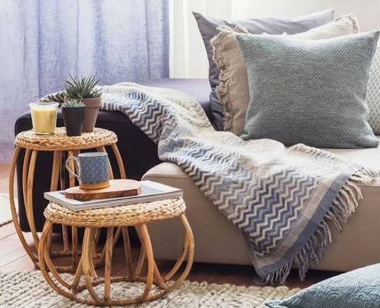 Juego de cama en tonos rosa suave, con cojines y manta blanca en un ambiente luminoso.