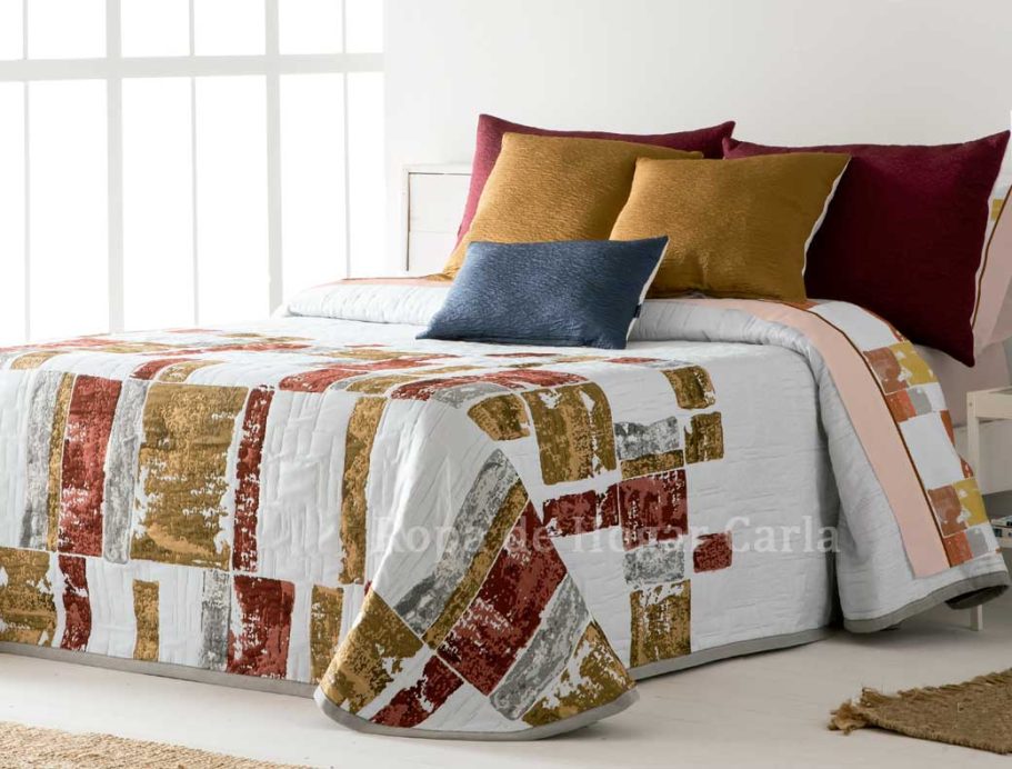 Ropa de cama con diseño geométrico en tonos cálidos y almohadas decorativas.
