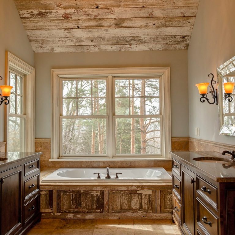 Baño con bañera, muebles oscuros y ventanas grandes con vista al exterior.
