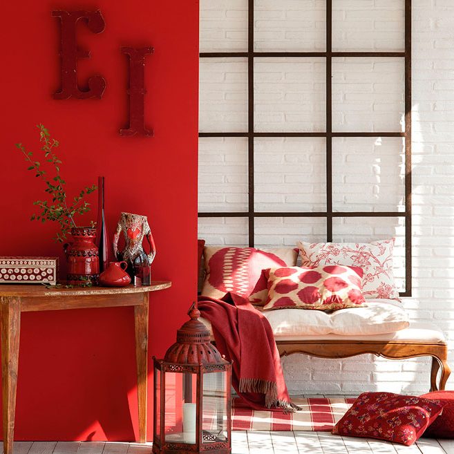Habitación con paredes rojas, muebles de madera y detalles en tonos rojos y blancos.