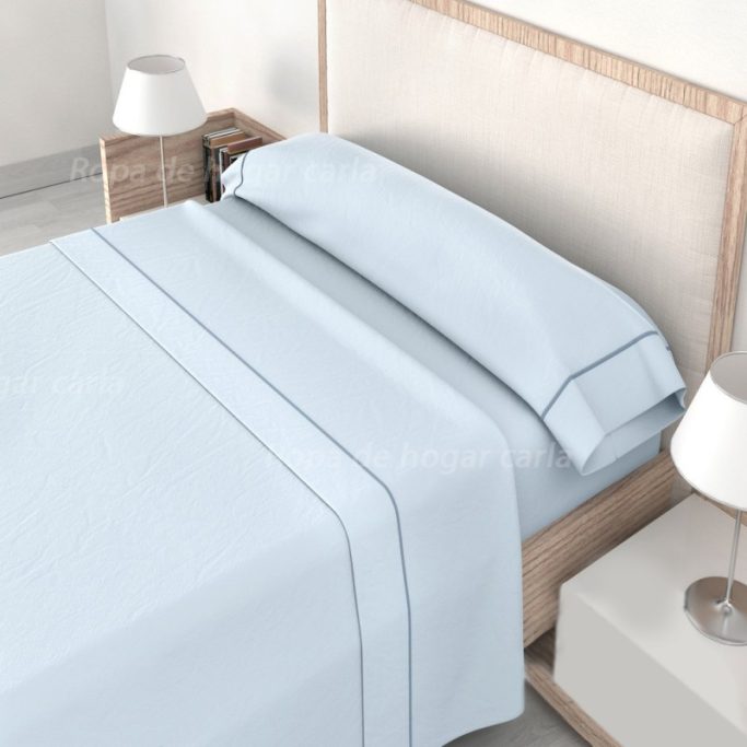 Cama con sábanas azul claro y cabezal de madera, junto a lámparas de mesa.