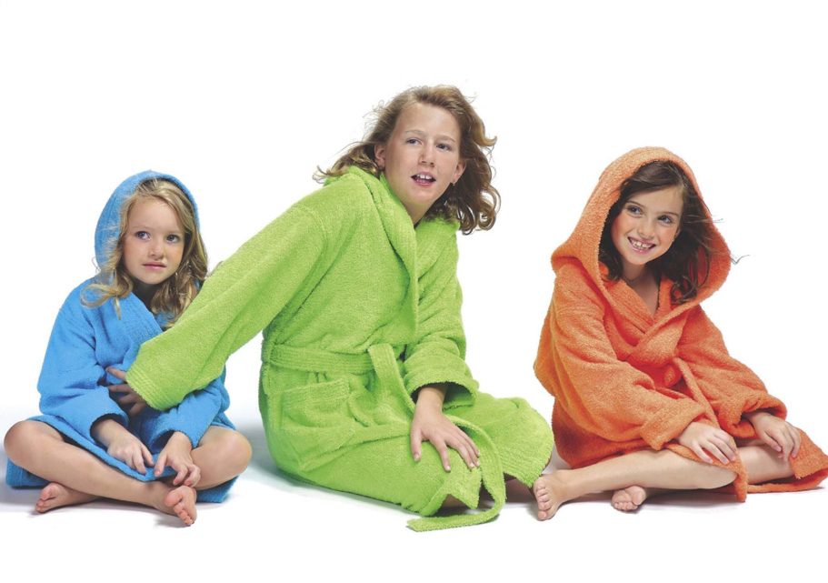 Tres niñas sentadas en toallas de baño de colores: azul, verde y naranja.