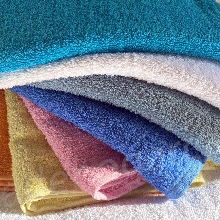 Toallas de diferentes colores apiladas, incluyendo azul, rosa y amarillo.