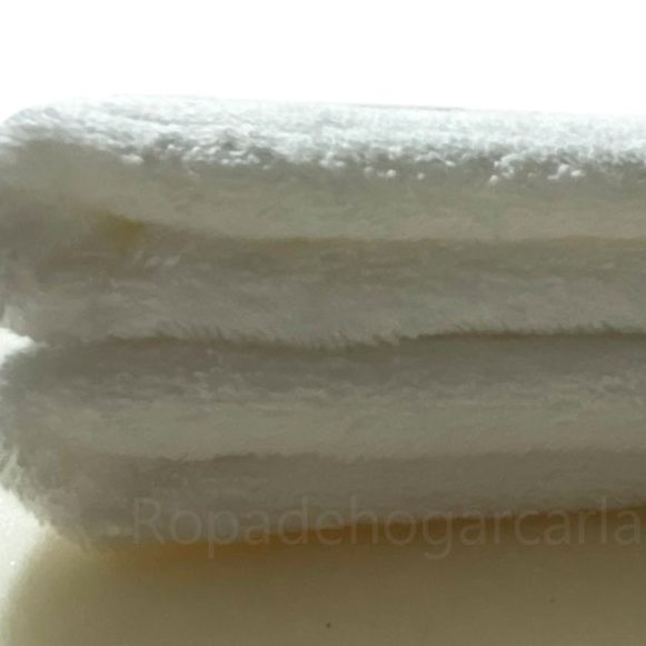 Toallas de diferentes colores apiladas: amarillo, naranja, azul, gris, rosa y blanco.