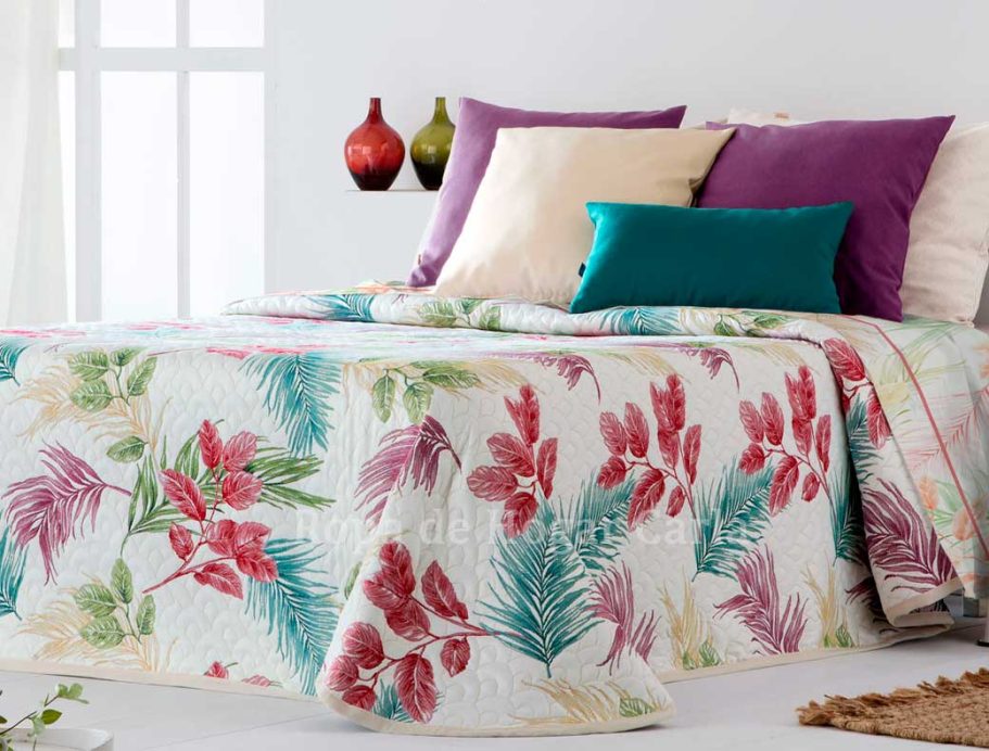 Colcha floral colorida con almohadas moradas y verdes sobre una cama. Decoración minimalista.